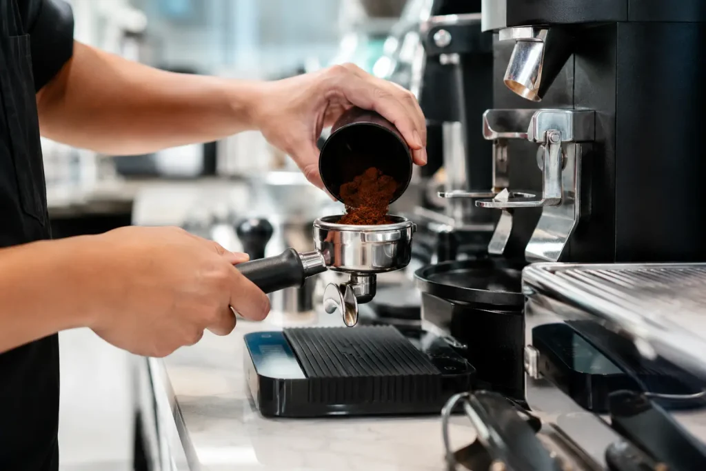 barista przygotowujący espresso przy profesjonalnym ekspresie i młynku