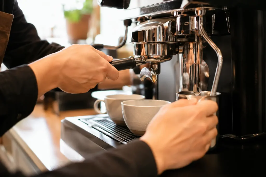 barista przygotowujący kawę za profesjonalnym ekspresem w jasnej kawiarni