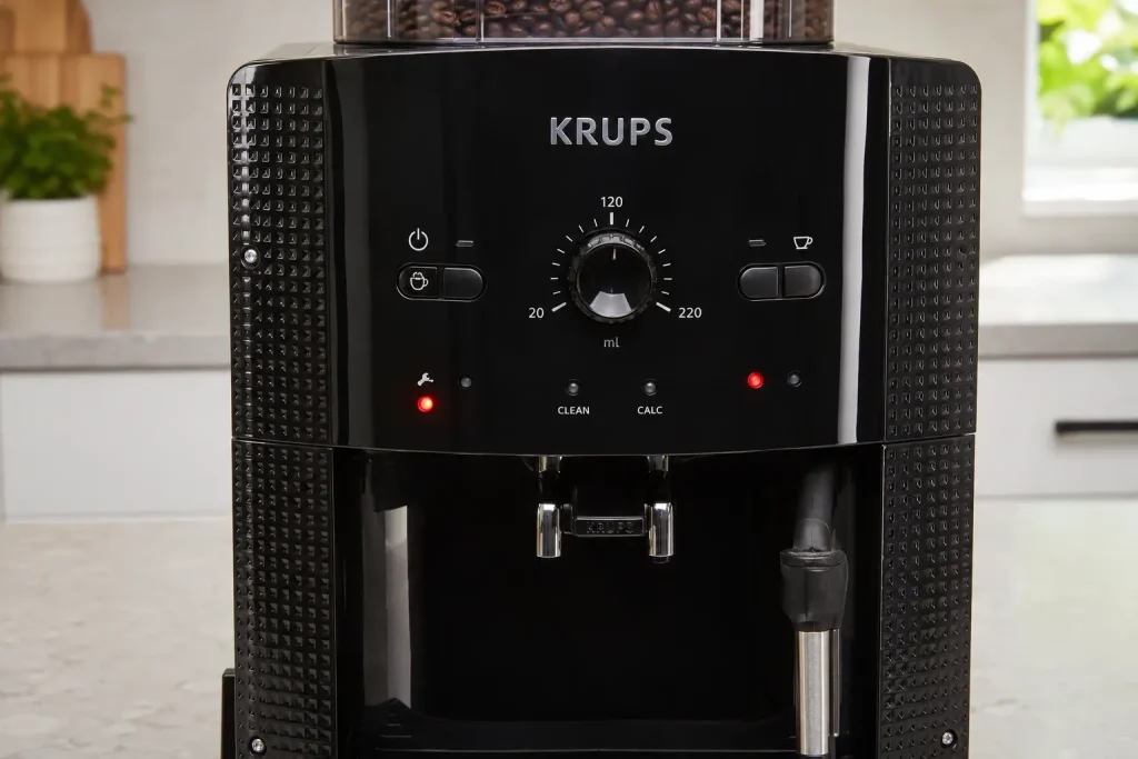 Czerwona kontrolka świecąca na panelu automatycznego ekspresu Krups stojącego na jasnym blacie kuchennym.